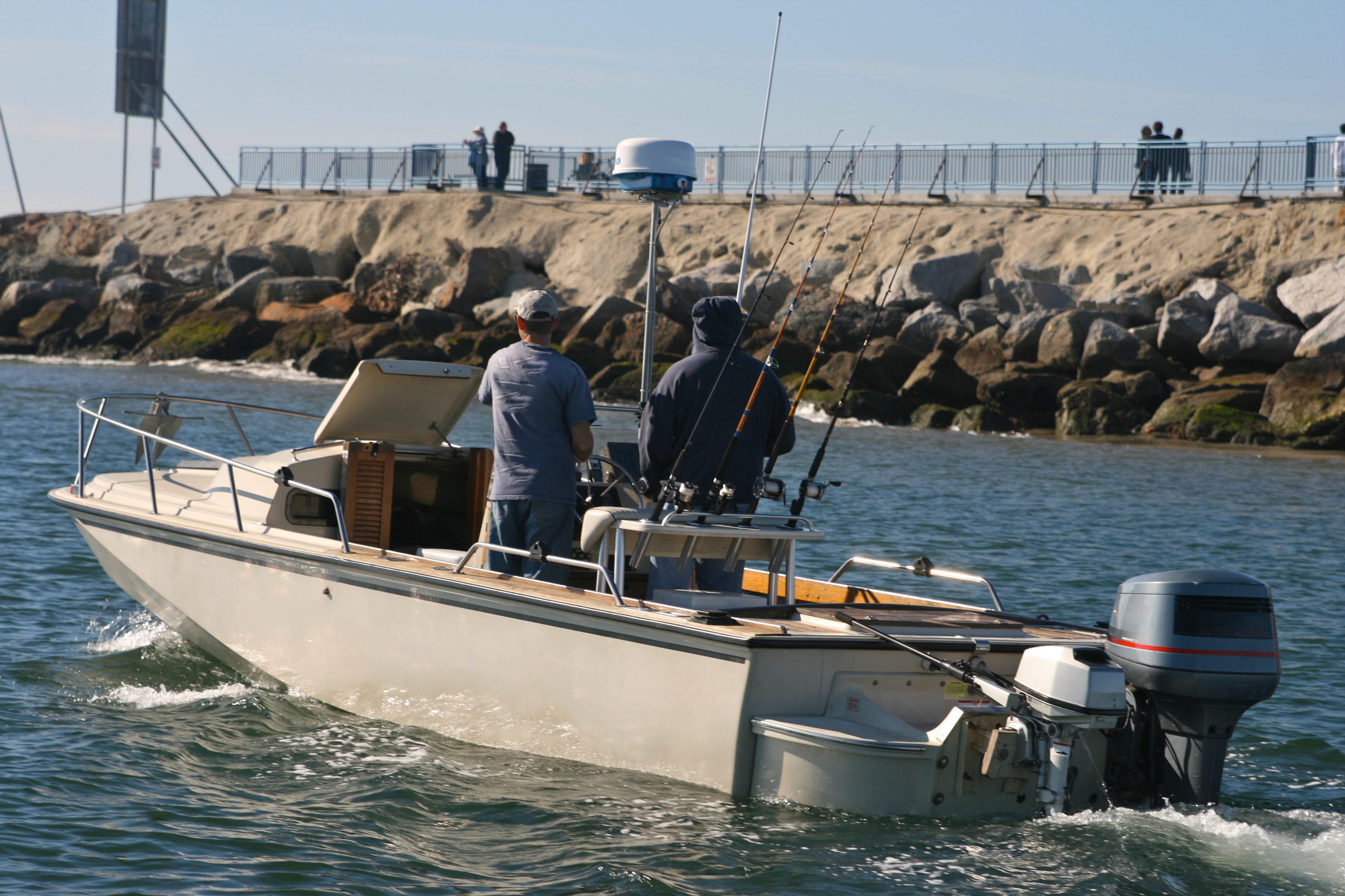 Two people fishing on a motorboat.