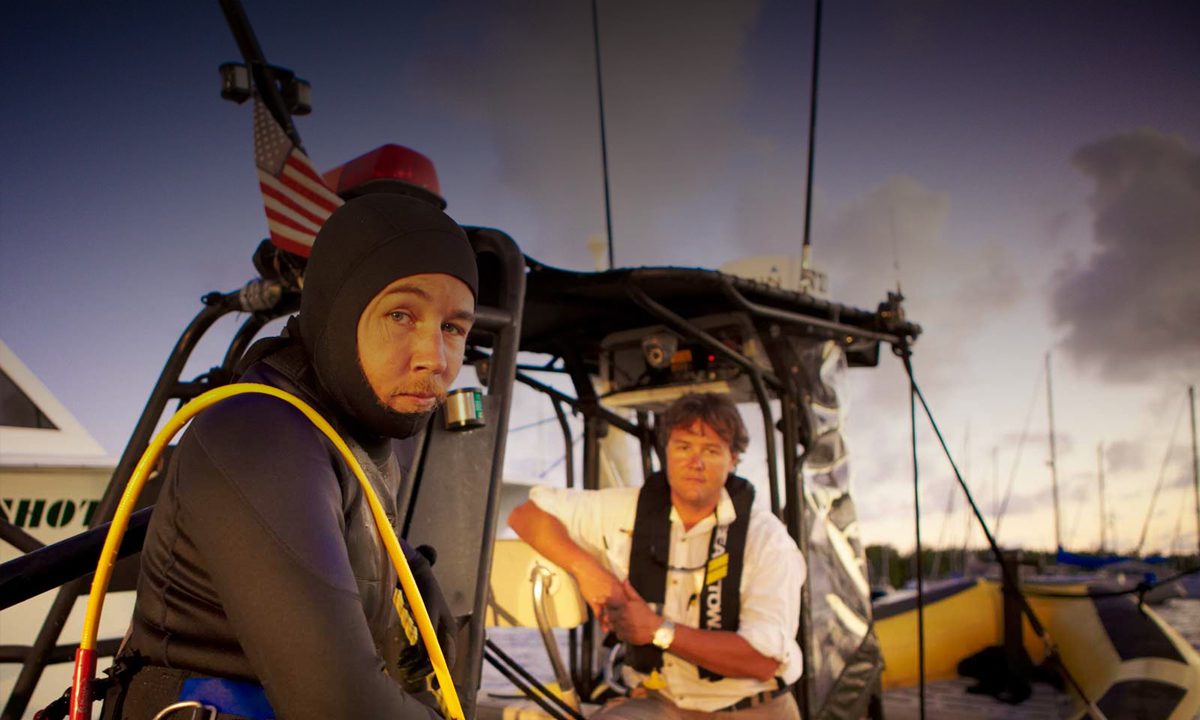 Two people on a boat at dusk, preparing for an activity.