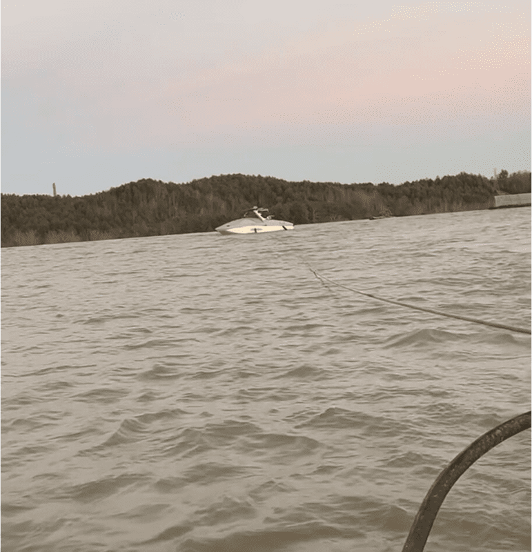 Boat sailing on a lake during sunset with hills in the background.