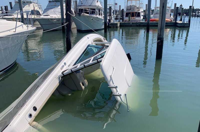 Partially submerged boat docked in a marina with calm waters.