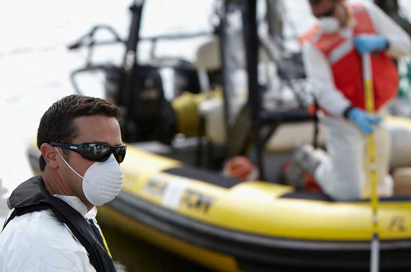 Person wearing a mask and sunglasses near a yellow inflatable boat.