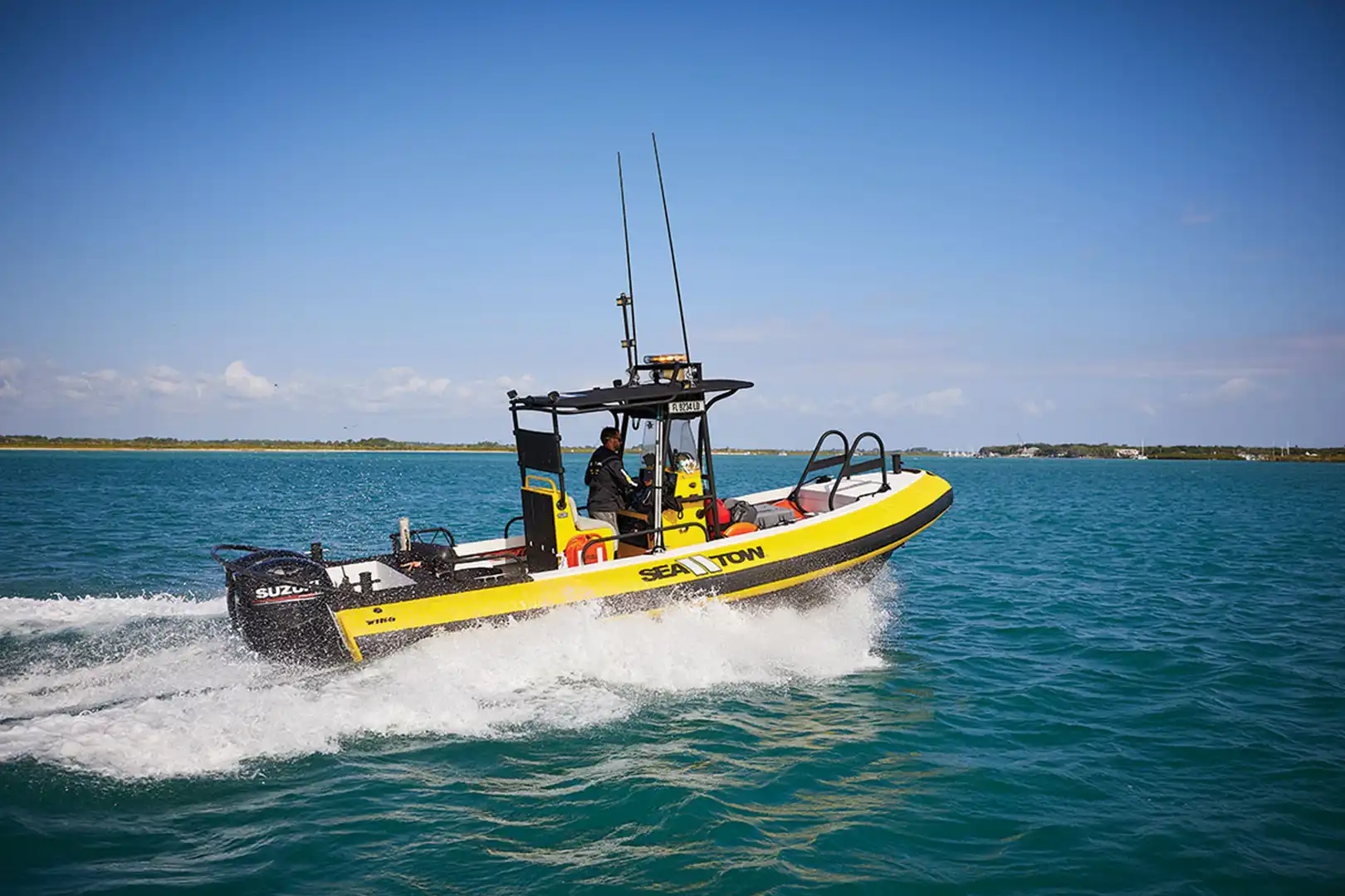 A yellow rescue boat speeding across the water on a clear day.