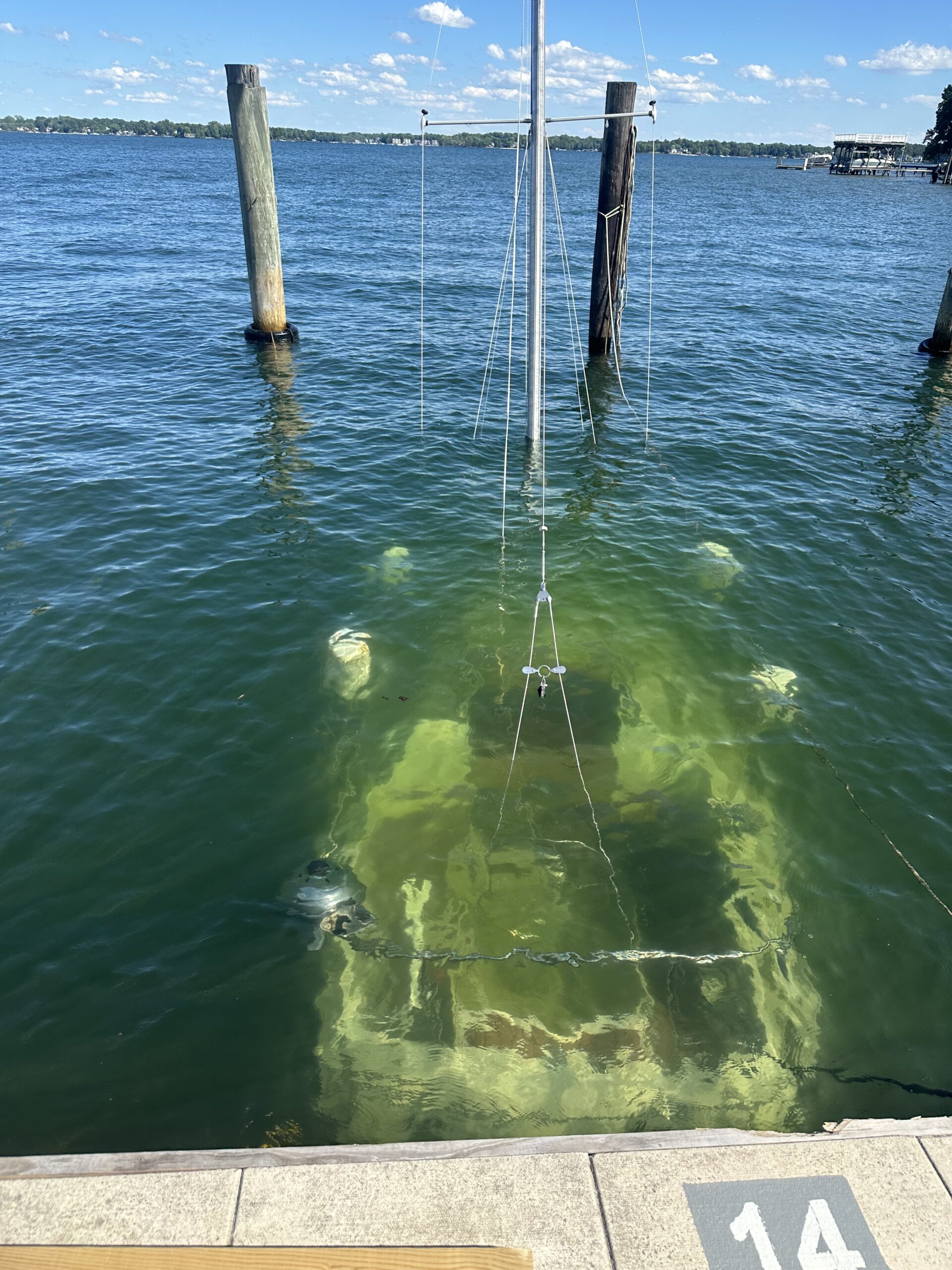 Sunken boat partially visible underwater near wooden posts.